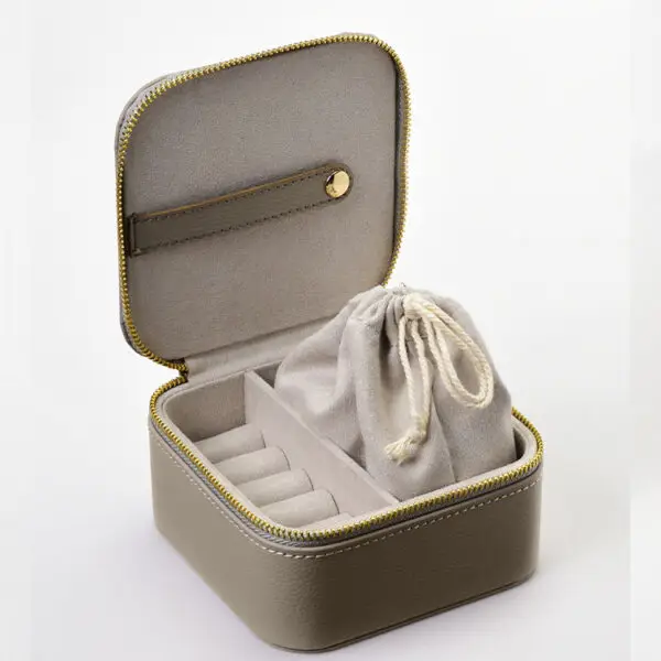 Custom leather travel jewelry box open with velvet-lined pouches, ring rolls and earring pads, embossed logo on lid