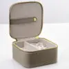 Custom leather travel jewelry box open with velvet-lined pouches, ring rolls and earring pads, embossed logo on lid