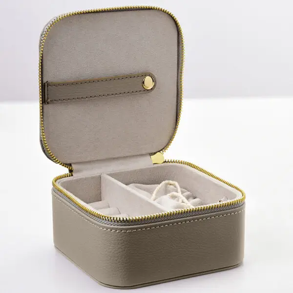Custom leather travel jewelry box open with velvet-lined pouches, ring rolls and earring pads, embossed logo on lid