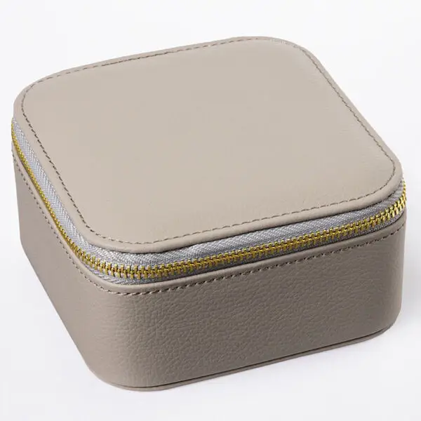 Custom leather travel jewelry box open with velvet-lined pouches, ring rolls and earring pads, embossed logo on lid