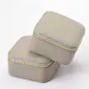 Custom leather travel jewelry box open with velvet-lined pouches, ring rolls and earring pads, embossed logo on lid